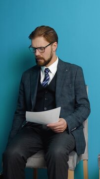 Person sits in chair reading papers while waiting for the job interview to start