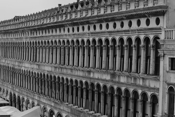 Naklejka premium Historic Renaissance building with rows of arches and columns on Piazza San Marco in Venice, Italy. Elegant symmetrical architecture in monochrome tones.