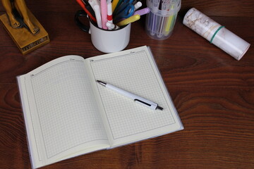 On the old table there is an old mug with old pencils, pens and a notebook
