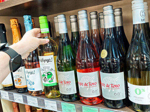 Maikop, Russia - June 04, 2025: Selection of wines on display in a store in Maikop Adygea Russia featuring a hand reaching for one bottle