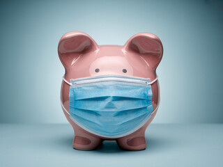 Protecting your savings during a pandemic: A piggy bank with a face mask shows financial health and security during economic uncertainty and global health crisis