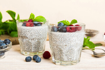 Healthy breakfast or morning with chia seeds vanilla pudding raspberry and blueberry berries on table background, vegetarian food, diet and health concept. Chia pudding with raspberry and blueberry