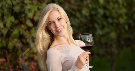 Woman drinks red wine in vineyard