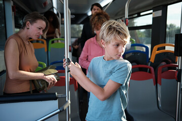 Boy using mobile phone traveling with family on bus