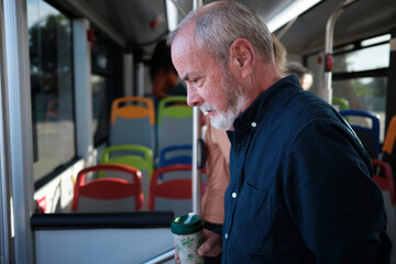 Senior man commuting on public transport with reusable cup