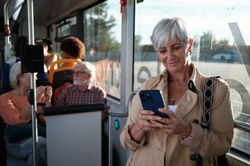 Senior woman using smartphone while commuting on bus