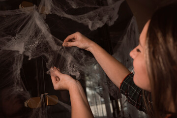 Woman decorating home for Halloween with fake spider web