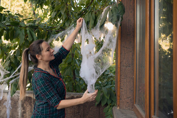 Woman decorating house for Halloween with fake spider web