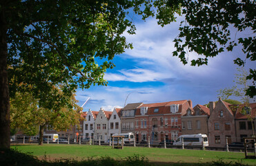 Bruges, Belgium – September 12 2025: Editorial image of traditional Flemish architecture in Bruges, Belgium, showing colorful historic houses and a public green area under a bright blue sky.