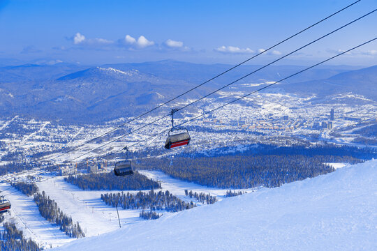 View from mount peak Zielonaya on Sheregesh ski resort and Altai mountains or Gornaya Shoria. Active winter rest,  ski slopes and Ski lift, clear blue sky and forest, beautiful nature, sport leisure.