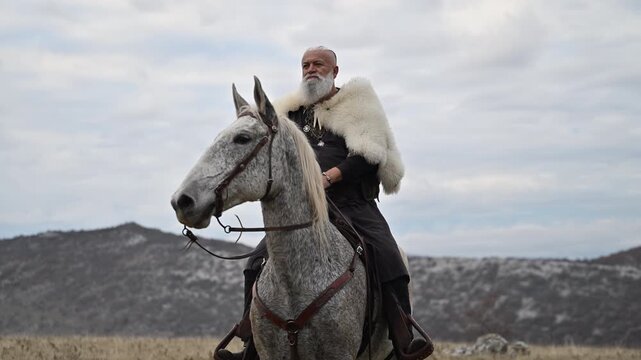 Elderly Viking warrior in fur cloak riding gray horse across open field at sunrise, mountains and distant cross behind him, moody cinematic Norse atmosphere cinematic slow motion 