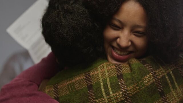 Close up shot of happy teenage daughter hugging mother holding school paper in principals office