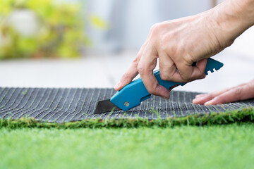 Close-up of man hand cutting and installing artificial grass at home