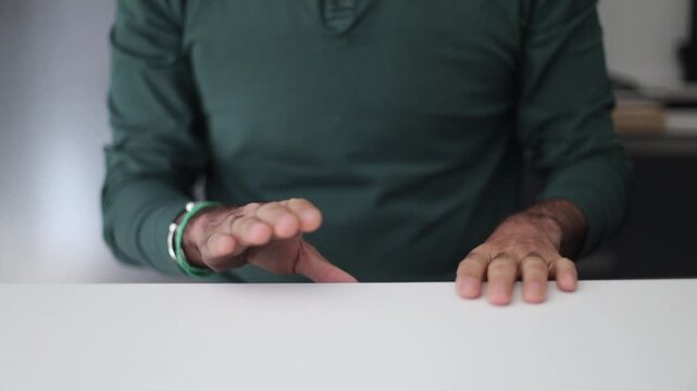Impatient man tapping fingers on white table