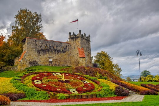 Picturesque view to former royal castle in Nowy Sacz, Poland at autumn day. Colorful flower clock on foreground