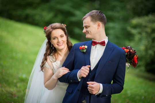 Young newlywed couple embracing in lush green summer park