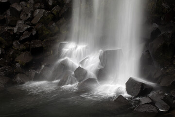 View of a cascade of water flowing powerfully over dark basalt columns, creating a misty spectacle of nature's raw beauty, Svartifoss, Sveitarfélagio Hornafjorour, Iceland.
