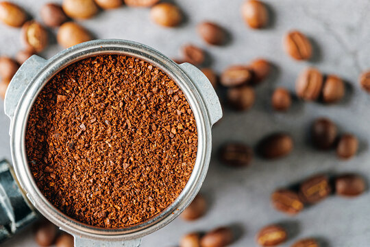 Ground coffee in portafilter or coffee ground in portable filter handle and coffee beans, Top view