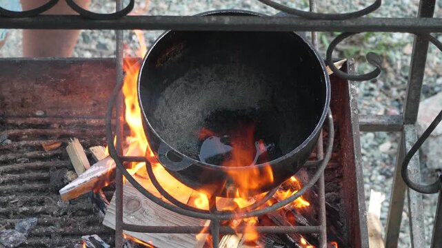 Cauldron, Cooking, Fire, heating oil in a large black pot over a blazing outdoor barbecue grill