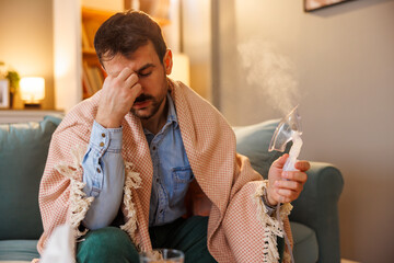 Man having flu and headache using inhaler