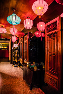 A richly decorated lounge with hanging lanterns, carved wood panels, and a golden statue. Candlelight and bar bottles add warmth and elegance.