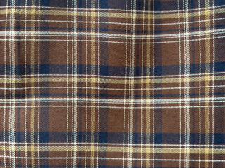 Close up of fabric with tartan pattern. In brown, white, and blue color. Flannel or tartan style is very common in scarf, shirts, and fashion industry. Seamless background texture.
