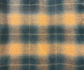Close up of fabric with tartan pattern. In blue and yellow color. Flannel or tartan style is very common in scarf, shirts, and fashion industry. Seamless background texture.