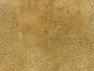 Sparkling yellow gold textured paint with glitters washed on a wall or panel, seamless background...