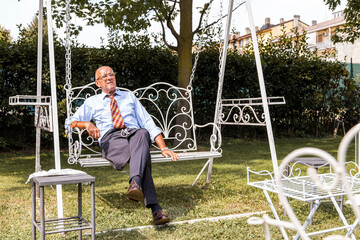 Senior man relaxing on garden swing contemplating retirement