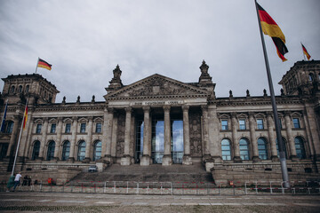 Obraz premium Majestic view of the historic Reichstag building in Berlin with German flags waving.