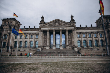 Obraz premium The historic Reichstag building in Berlin adorned with German and European flags.