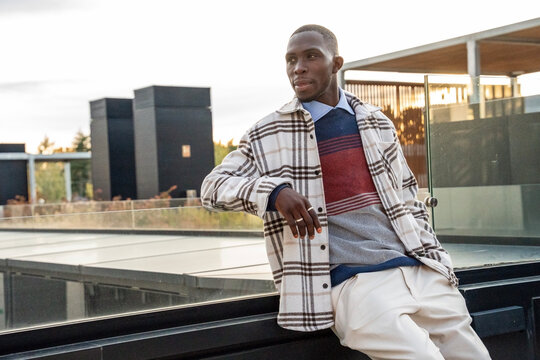 Fashionable man enjoys a sunset view from a modern rooftop terrace in the city