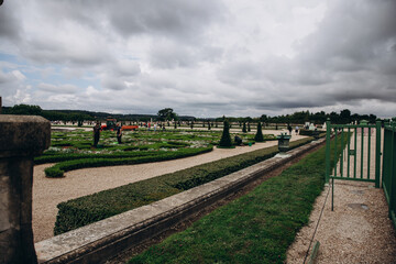 Beautiful landscape view of a formal garden with people enjoying a cloudy day.