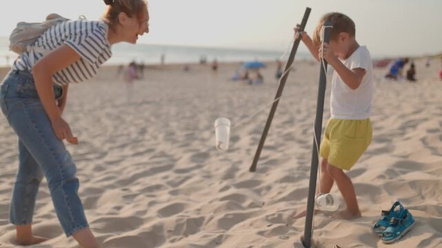 Mother and son building together a diabolo structure on a sandy beach