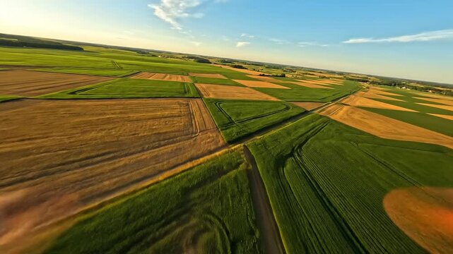 High aerial drone shot tracking over a vast checkerboard pattern of farmed fields creating a striking geometric rhythm across the landscape overhead view, repetition, farmed fields
