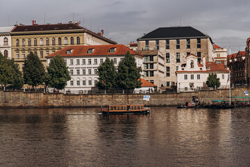 Charming riverside architecture with boats along the waterfront under a cloudy sky.