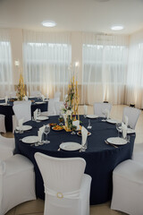 Elegant banquet hall setup with round tables and white covered chairs for a formal event.