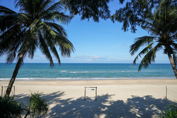 A tropical paradise framed by palm trees at Lang Co Beach, featuring golden sand, calm turquoise ocean waters, and a clear blue sky 