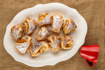 Fragrant mini strudel with apples on a white ceramic dish, top view. macro.