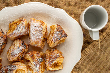 Fragrant mini strudel with apples on a white ceramic dish, top view. macro.