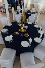 Elegant event dining table setup with floral centerpiece and white chairs.