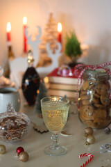 Cookie jar, tea, wine, nuts, books, lit candles and Christmas decorations on the table. Cozy Christmas hygge at home. Selective focus.