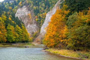 Raft with tourists floating along Dunajec gorge in Pieniny National Park., Poland at sunny autumn day. Dunajec river - popular tourist spot for boat rafting in Poland