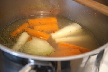 Traditional homemade Hungarian chicken soup simmering in a cooking pan in close-up view.