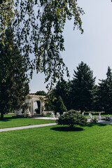 Outdoor wedding ceremony setup in a lush green garden with a decorated arch.