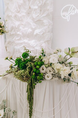 Elegant wedding floral arrangement with white roses and green accents.