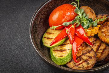 Colorful grilled vegetable assortment with zucchini, eggplant, bell pepper, tomato and corn served in a rustic dark bowl