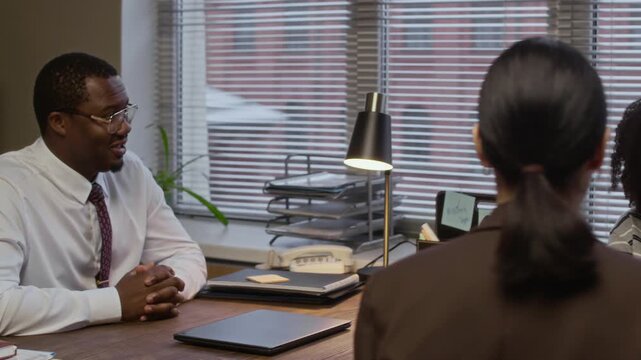 Pan shot of female psychologist and male African American principal having appointment with teenage girl and her mother in school office