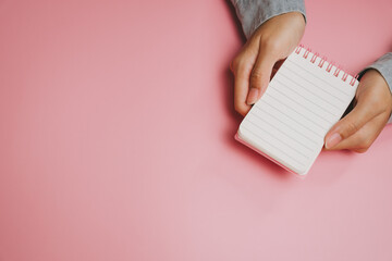 Blank notebook hands holding pink background empty page spiral notebook writing pad note taking female hands minimalistic clean surface isolated object casual wear personal organizer stationery