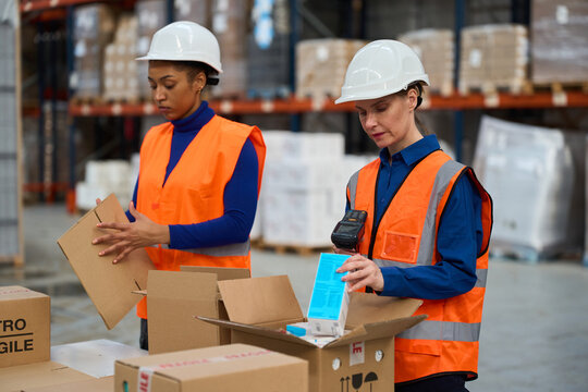 Women warehouse workers packing packages for shipping